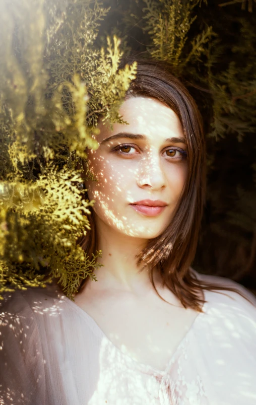 a young woman is posing next to bushes