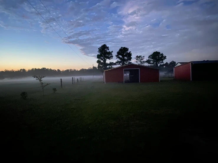 the dark fog is covering a farm and pasture