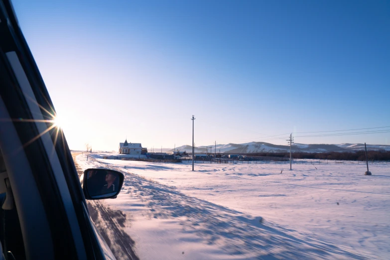 the sun shines on the snow covered field outside the car