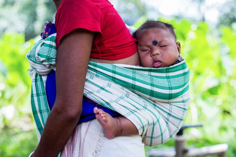 a woman holding a baby wrapped in a wrap