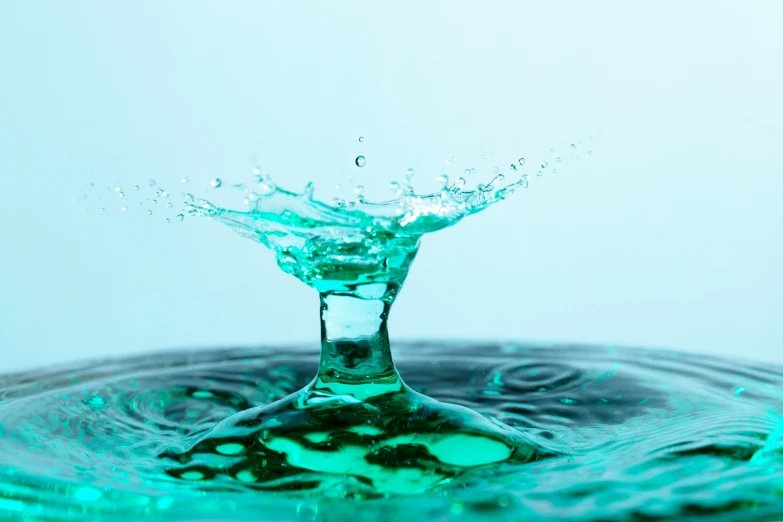 a blue liquid splashing in water, with a white background
