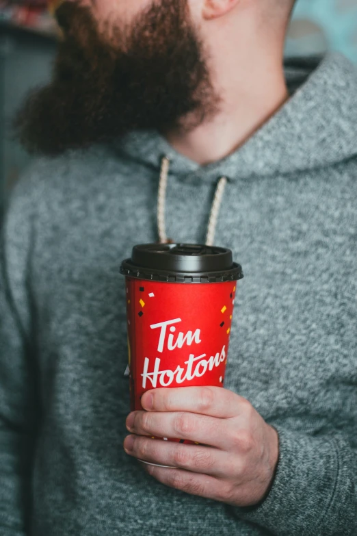 a man with a beard holds a cup