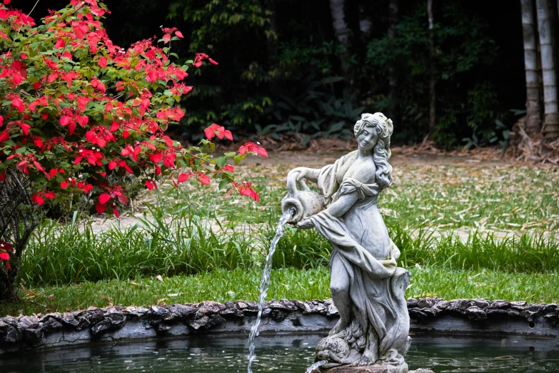 a statue sitting on top of a rock next to a pond