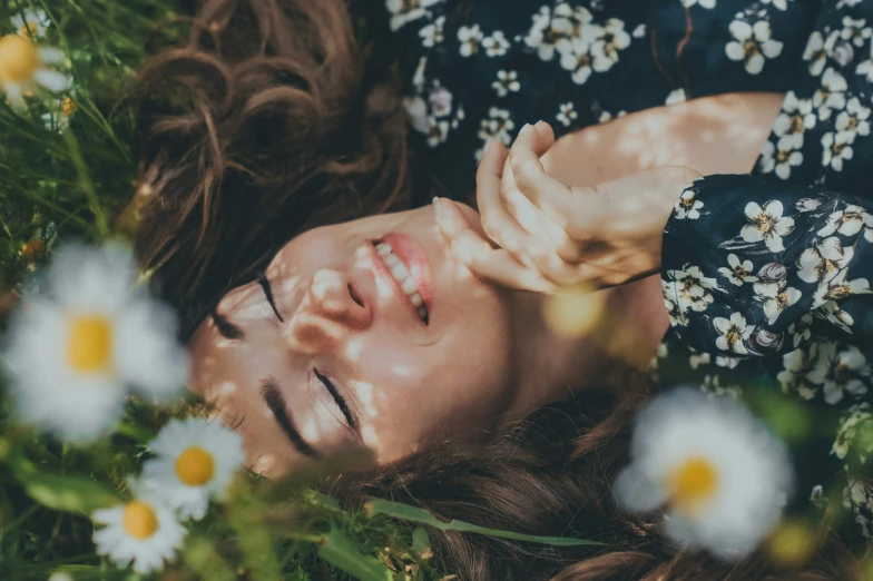 woman laying in grass with daisy flowers