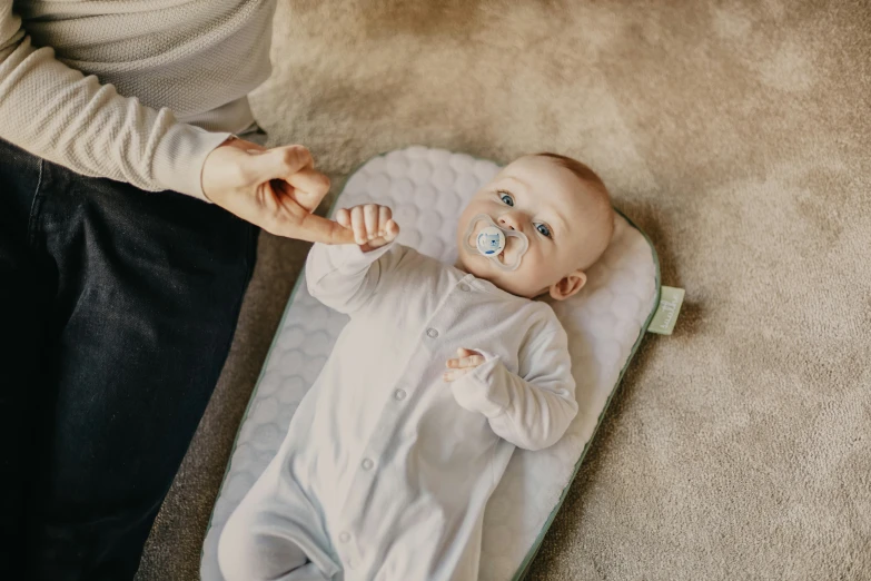 a baby in a footie being hed by a woman