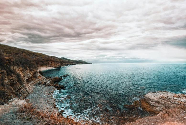 a cloudy view of the ocean from above a cliff