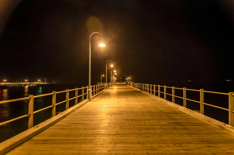 a long wooden dock at night with street lamps