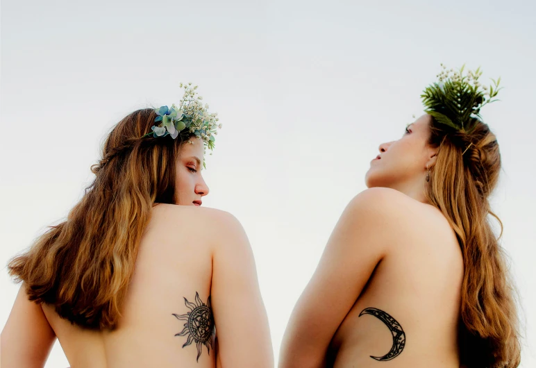 two women wearing sun and moon tattoo back to back