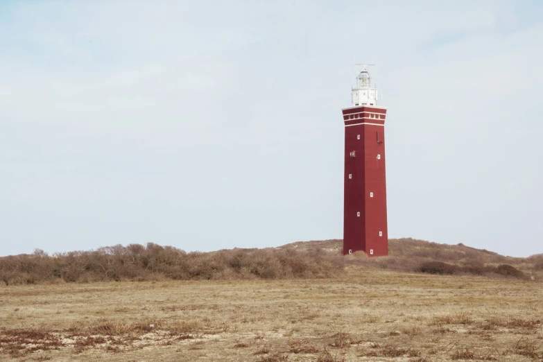 a lighthouse on top of a hill covered in grass