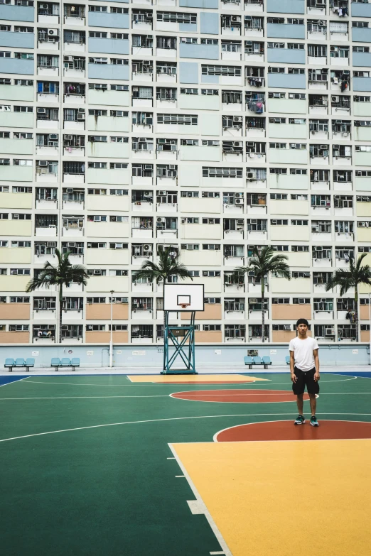 a man standing on the basketball court in front of a large building