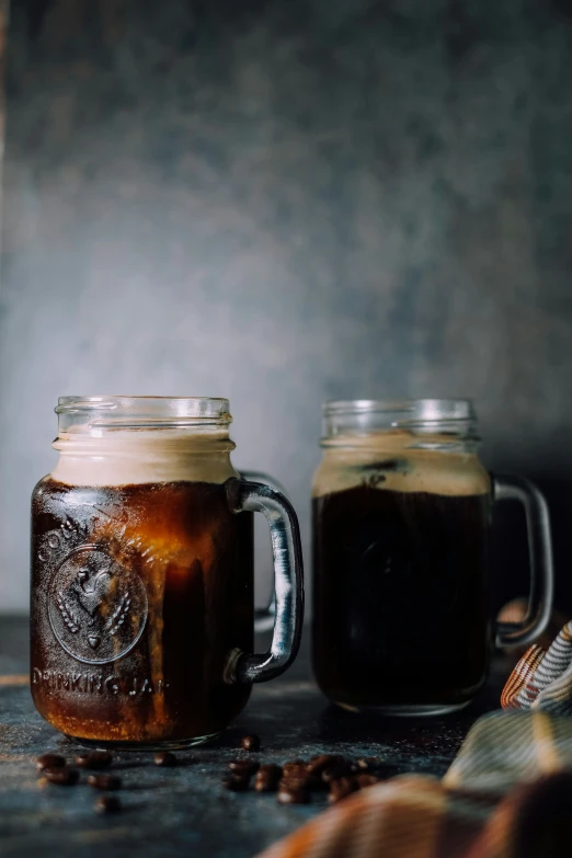 two mugs are full of beverage and one has a spoon in it