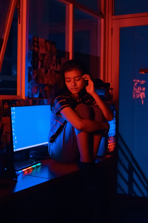 woman sitting at desk with laptop on illuminated by blue and red lights