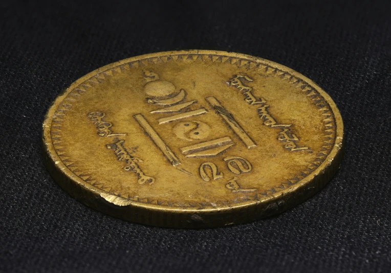 an indian coin is sitting on a black surface