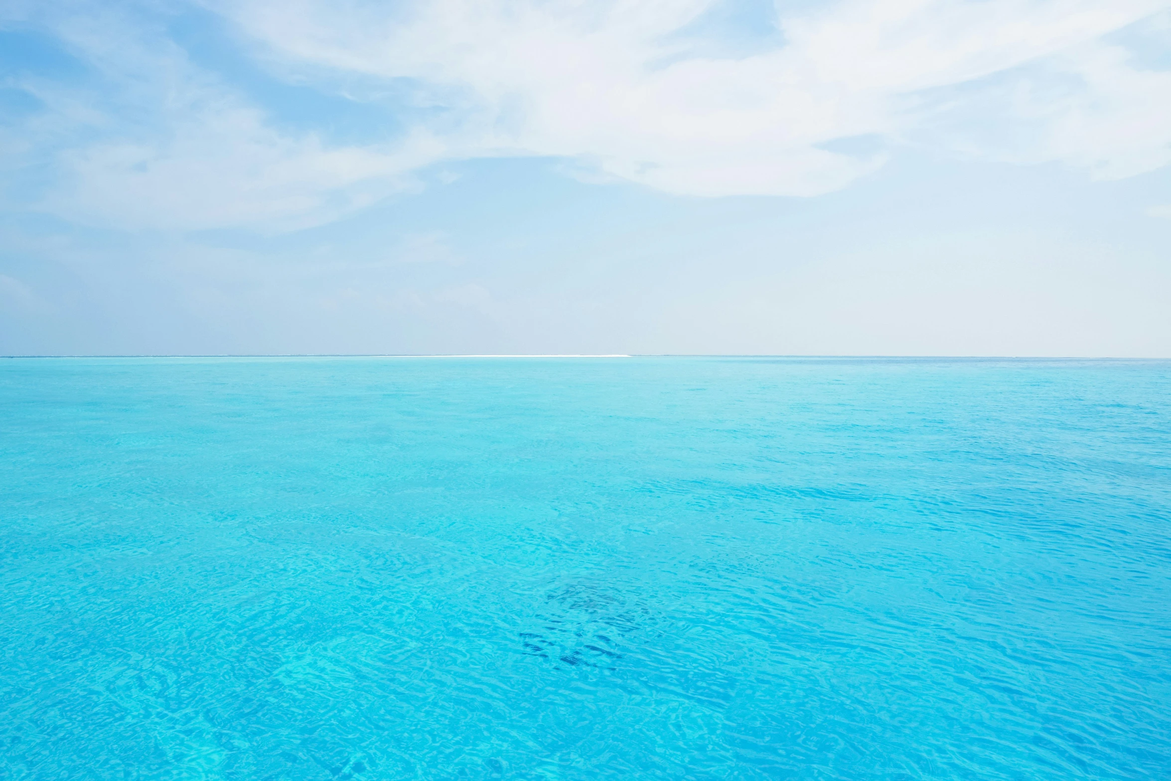 a clear blue ocean is seen against the sky