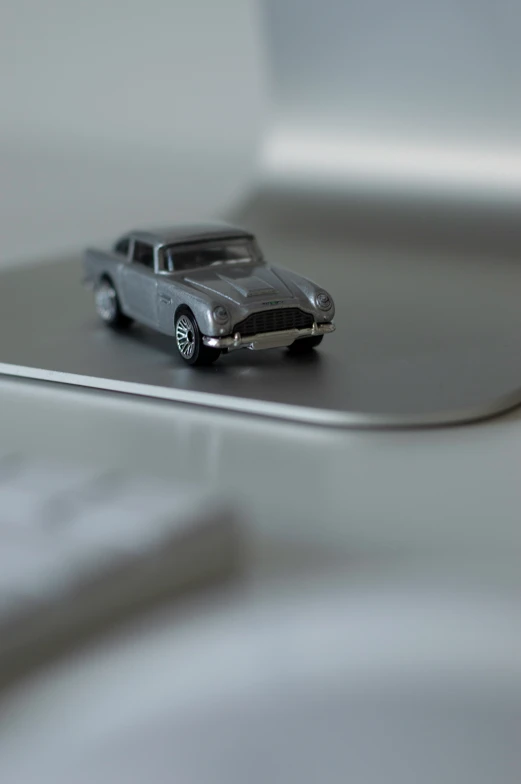 a silver toy car sitting on top of a table