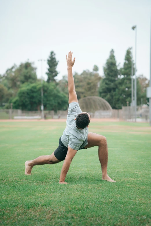 a man doing a yoga on top of a green field