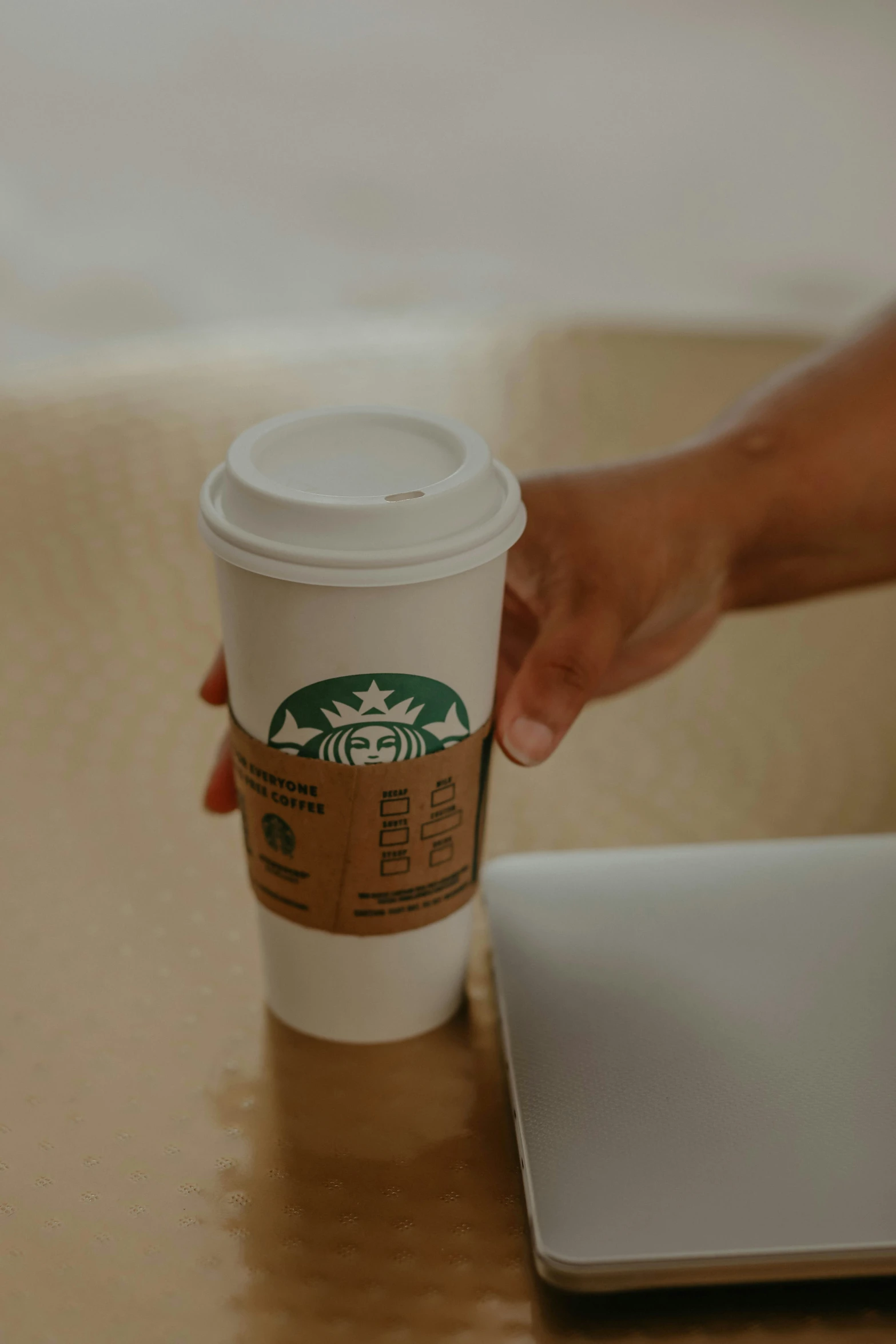 a person reaching for a coffee cup sitting on a desk