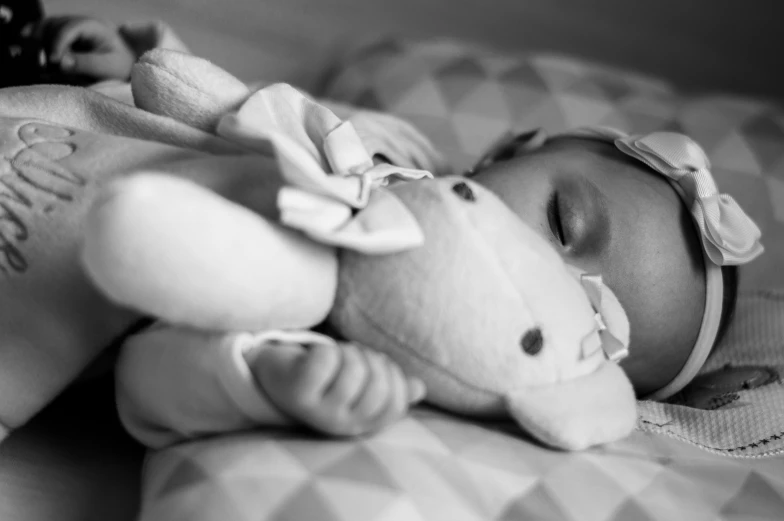 a black and white pograph of a baby sleeping on a bed
