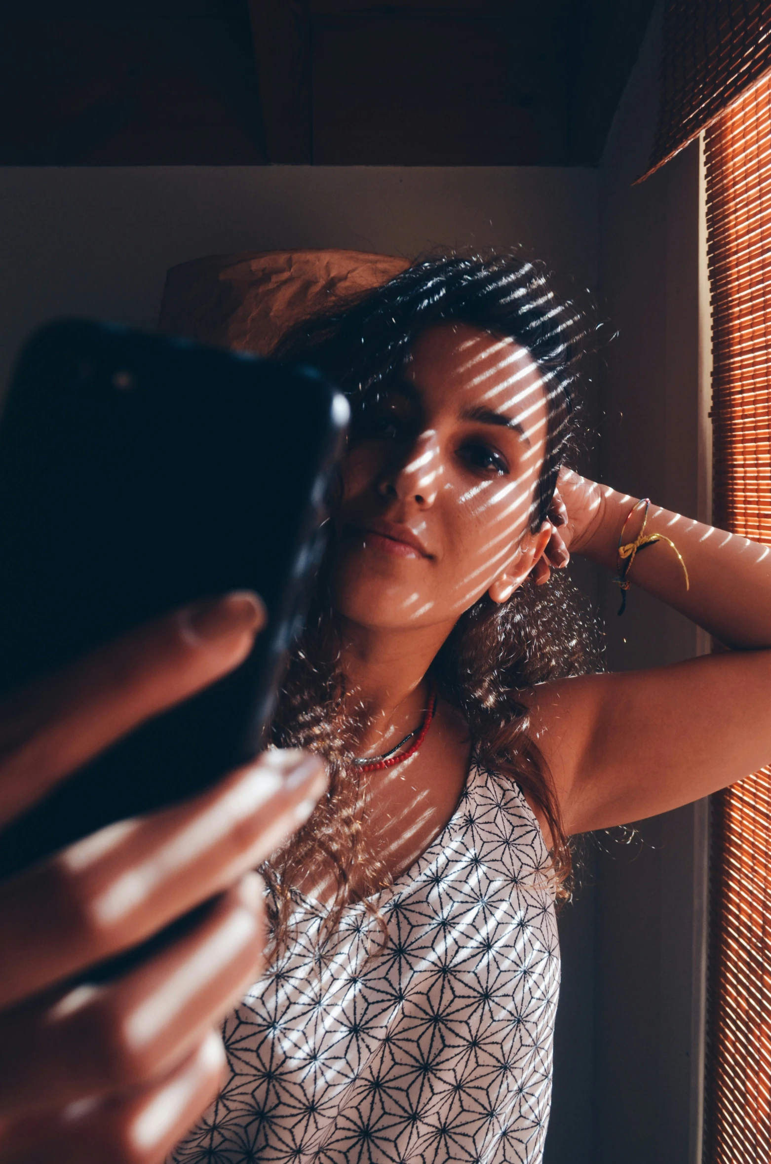 a woman holding up a smart phone next to a window