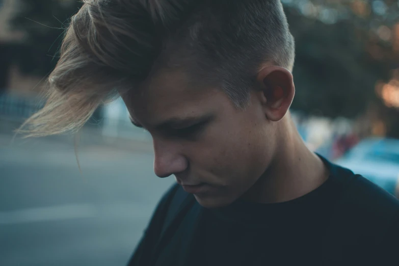 a young man wearing a black shirt looks down at his cell phone