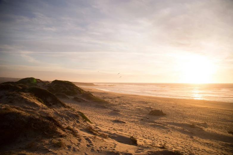 a sandy beach near the ocean with a bright sun