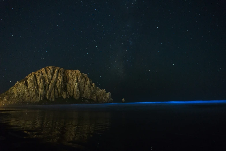 a lone rock sits on the shoreline in the middle of water