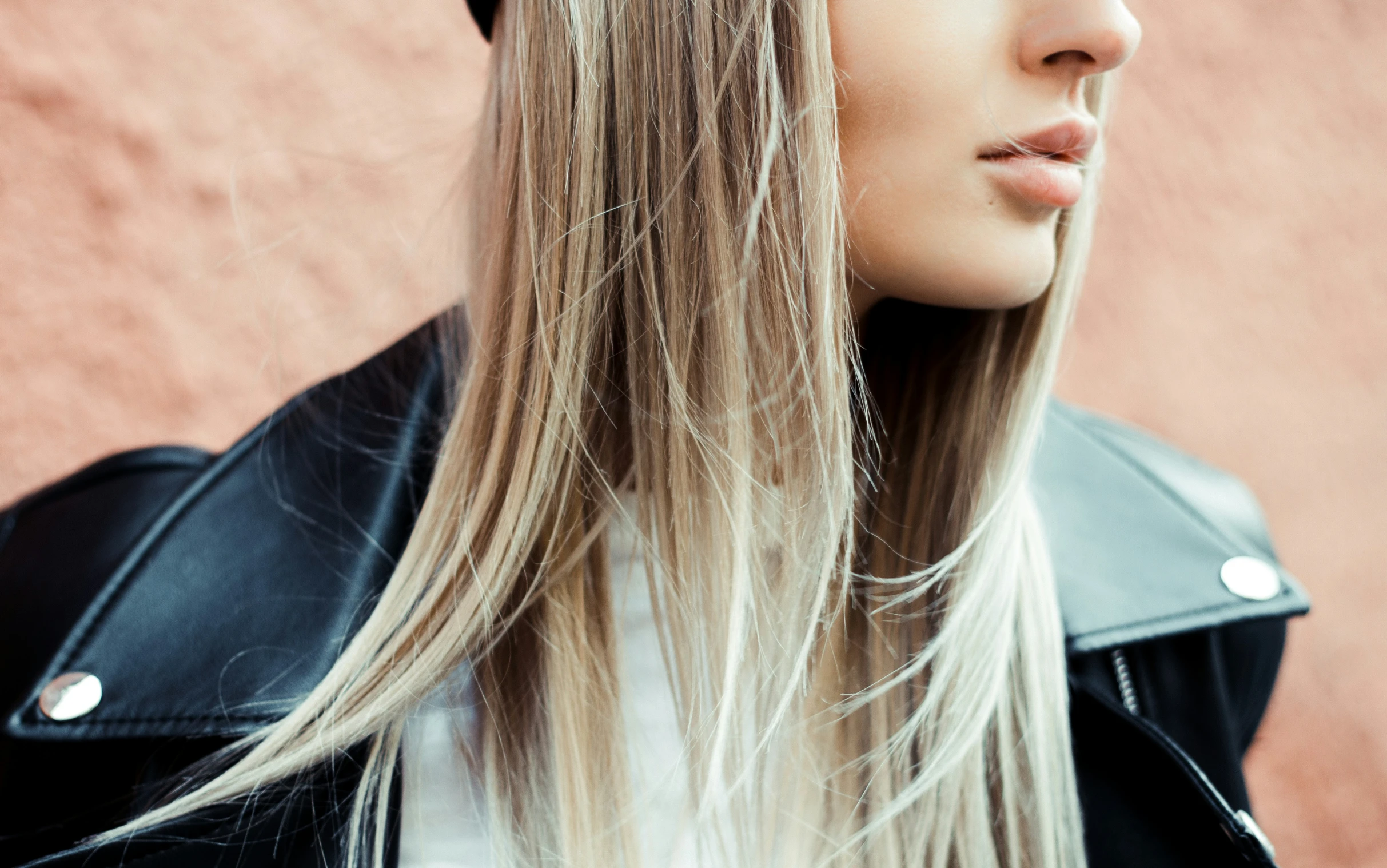 a woman is posing in front of a wall with long hair