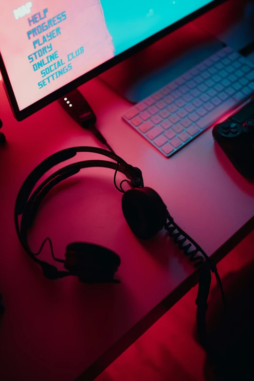 a red desk with a laptop a keyboard and headphones