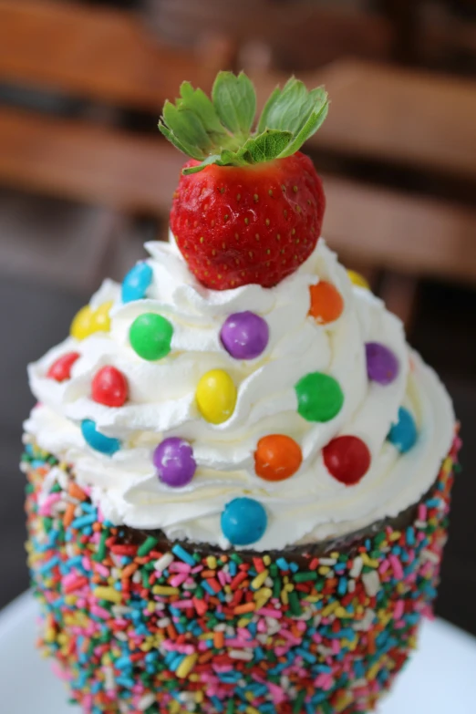 a rainbow colored cupcake decorated with a strawberry on top