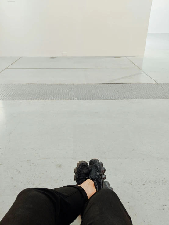 legs in black shoes standing next to a white sculpture