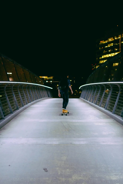 a skateboarder rides across a bridge at night