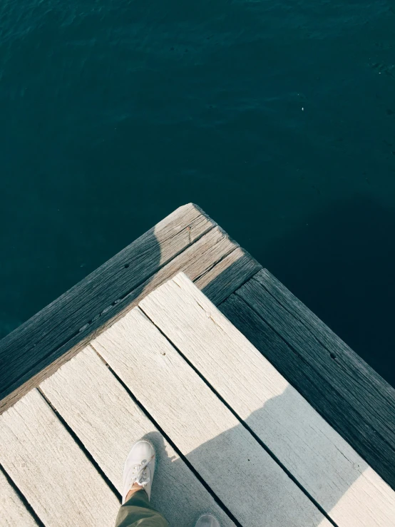 a pair of feet on a pier near water