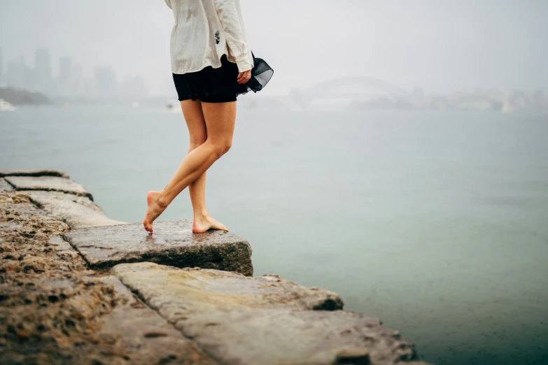 a woman holding an umbrella on top of a concrete wall