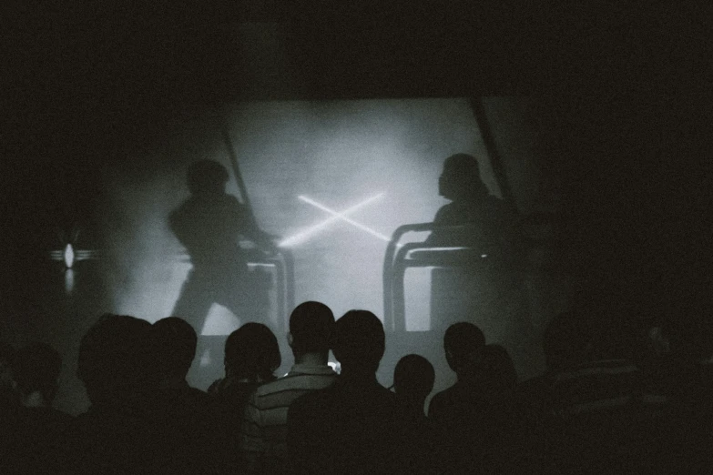 a couple of people standing in the dark by some curtains