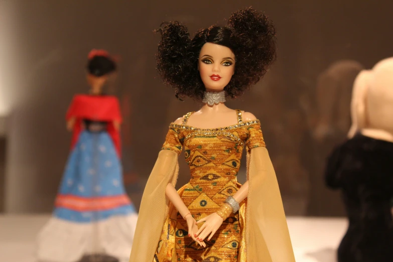 a doll is wearing a yellow dress with gold embroidery