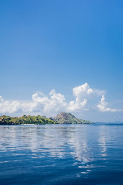 an island is seen in the water, under a blue sky