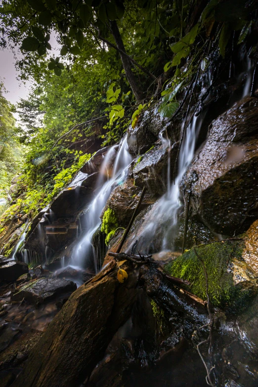 waterfall falls flowing off rocks and into the woods