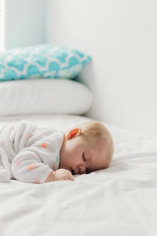 a baby laying on a bed with its eyes closed