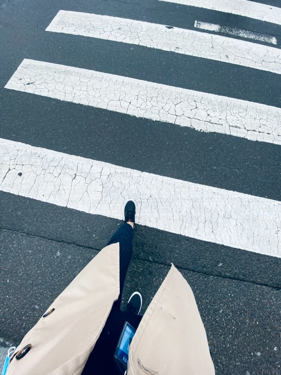 a person with their legs crossed walking across a street