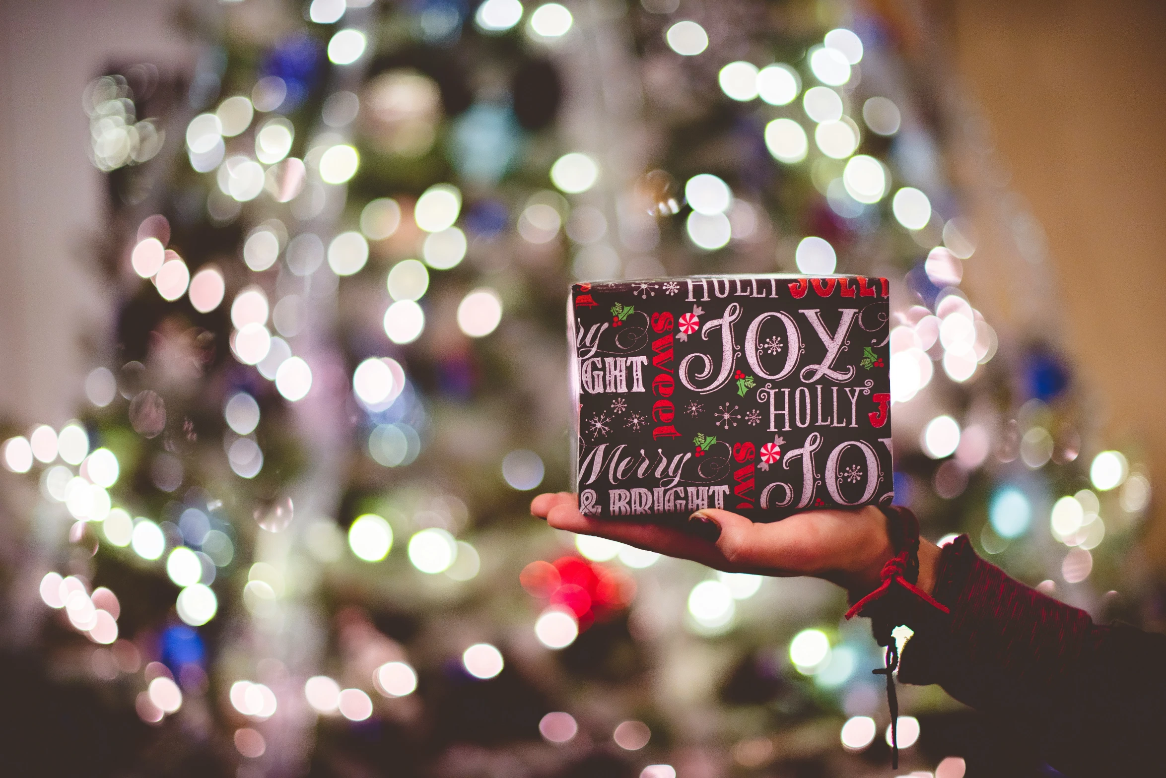 a person holding a christmas card in front of a christmas tree