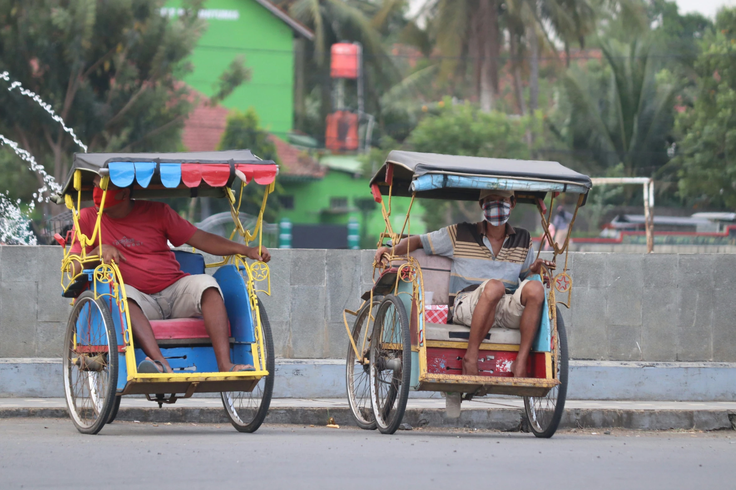 a man drives two rickshaws with people riding on them