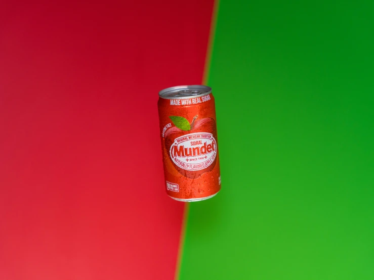 a can of red soda on top of a green and pink background