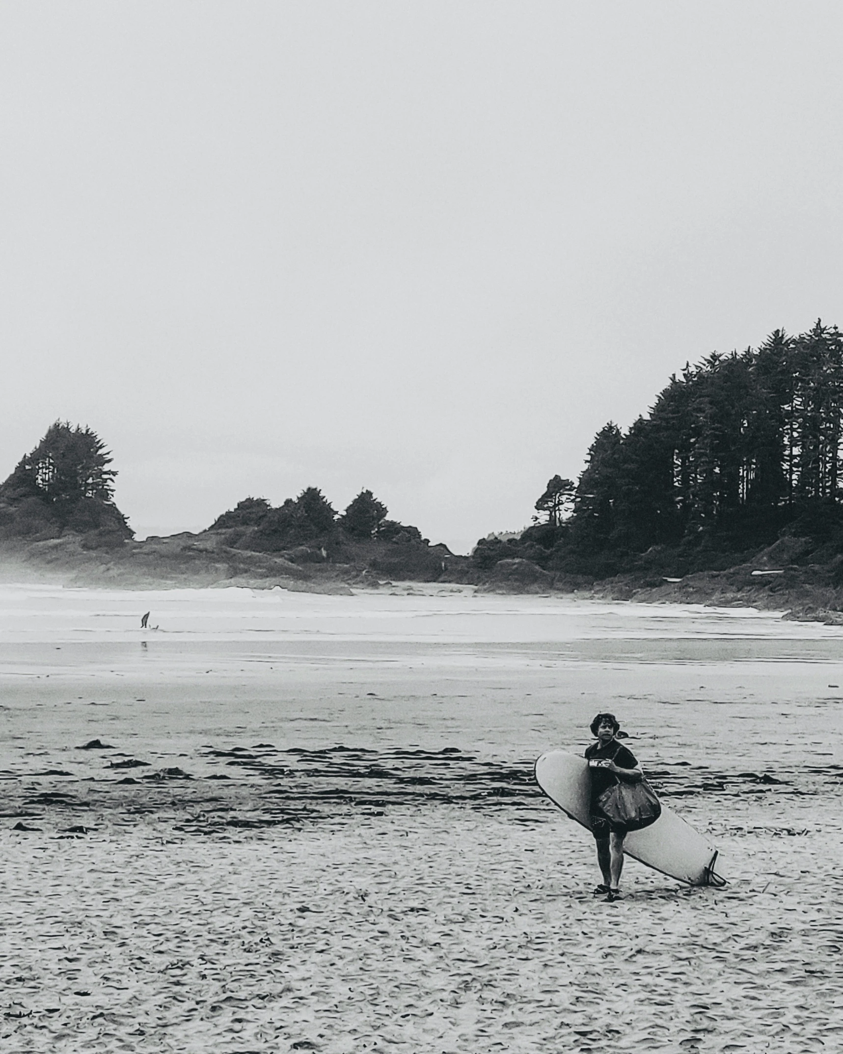 a woman walking on the beach with a surf board