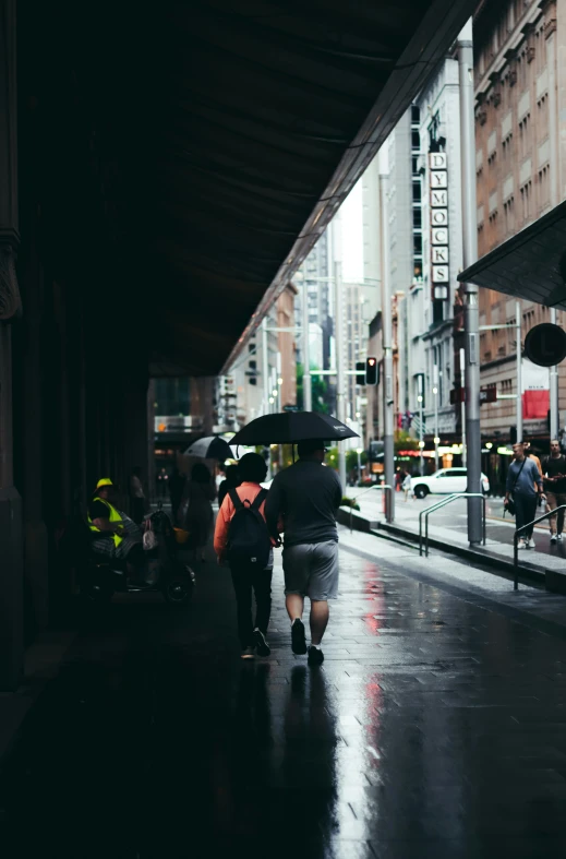 the people are walking down the street together in the rain