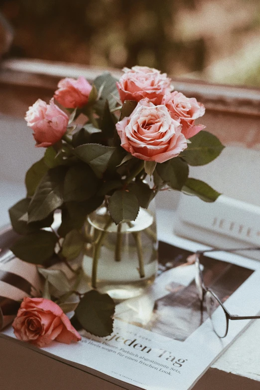 a glass vase of roses on a table