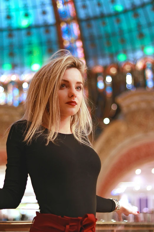 a woman with blonde hair poses on a balcony