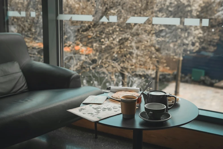 a coffee cup and a plate on a table next to a window