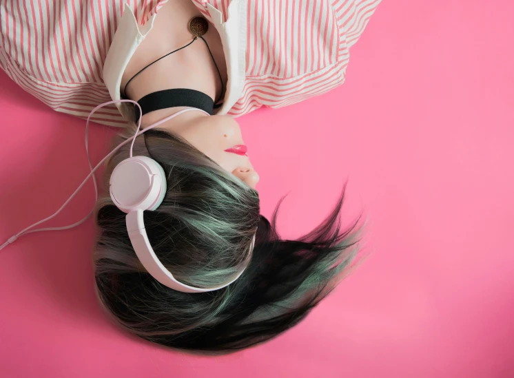 a girl with headphones lying on pink floor