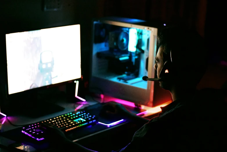 a man is sitting at a computer in a dark room