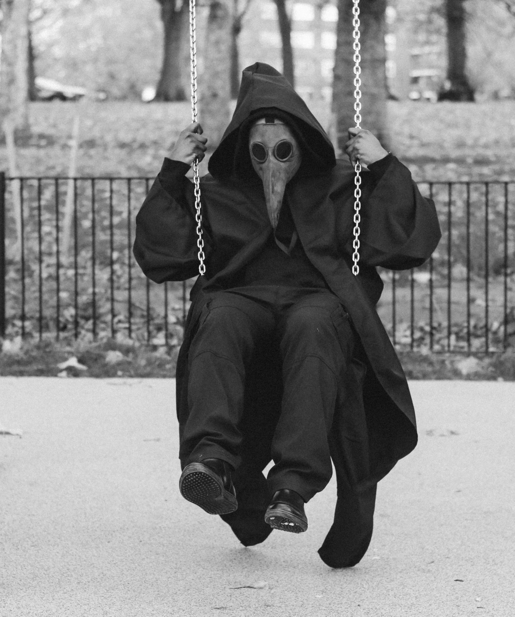 a person wearing a hood sitting on a swings swing